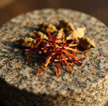 Macro shot of saffron threads and cardamom pods resting on a textured granite grinding stone, warm golden hour light, shallow depth of field, 35mm film.