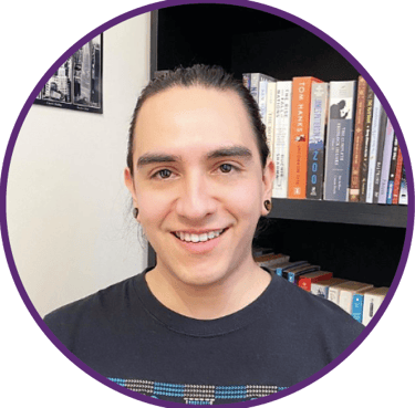 a man with a smile on his face and a bookcase in front of a