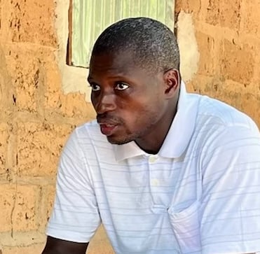 a man sitting on a bench in front of a brick wall