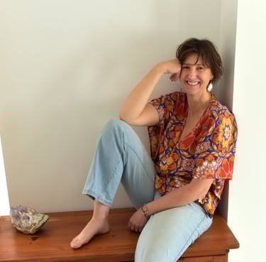 julie mansencaut sitting on a wooden bench with a bookcase