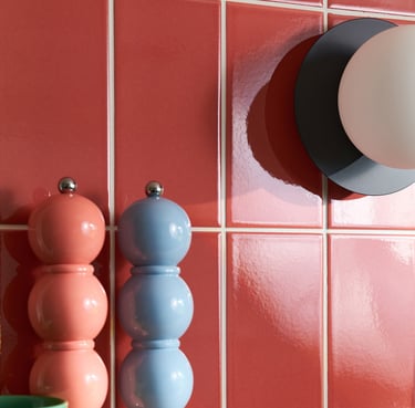 Glossy coral wall tiles with white grout in a modern kitchen splashback, featuring pastel pink 