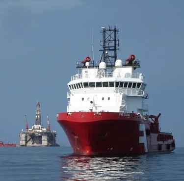 Red offshore supply ship Far Sound anchored near a semi-submersible oil drilling rig at sea.