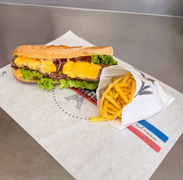 Sandwich steak cheddar ,dans une baguette, avec de la laitue et des oignons, accompagné de frites