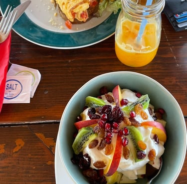 a bowl of fruit salad with a glass of orange juice