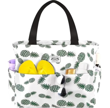 White pineapple print beach tote bag with yellow flip flops and sunglasses in outside pockets.