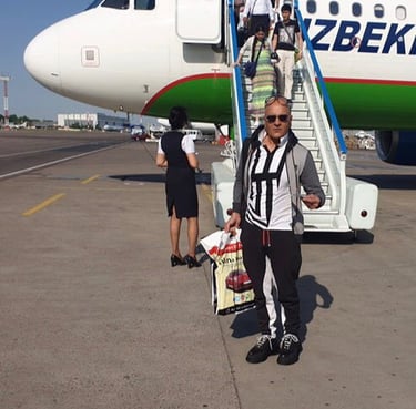 a man in a jacket and sunglasses is in front of Uzbekistan Airways Plane