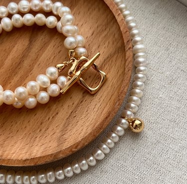 ein Holztablett mit einem Armband und einer Halskette mit goldener Verschluss