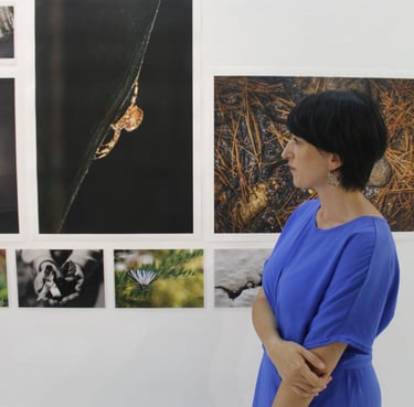 Asimina Georgakopoulou facing photographs during an exhibition by the Eyes of Light Organization