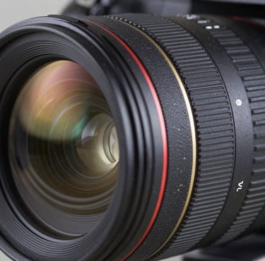A close-up photograph of a professional camera lens with reflections of a modern studio, charcoal black and slate blue tones, professional lighting, sharp focus.