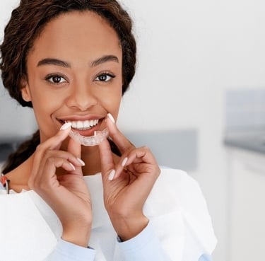 femme tenant des aligneurs transparents pour un traitement orthodontique de redressement de dents