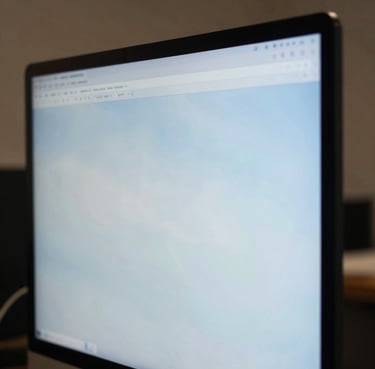 A close-up photograph of a designer in a North American / US creative studio, focused on a high-resolution screen reflecting soft sky blue tones.