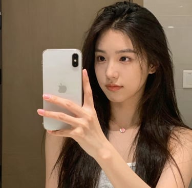 Portrait of a young Asian woman with long wavy brown hair and natural makeup.