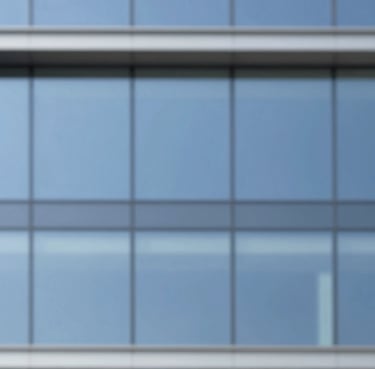 A minimalist wide shot of a contemporary building facade with large glass panels reflecting a clear blue sky, in a professional architectural style.