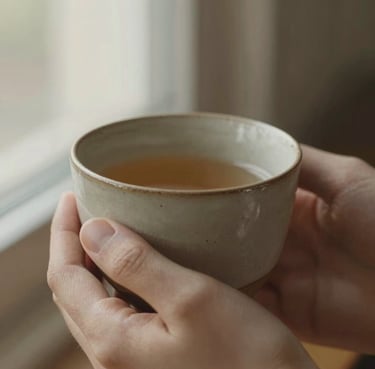 Macro close-up of hands holding a warm, textured ceramic cup, soft morning light filtering through a window, earthy tones, 35mm photography.