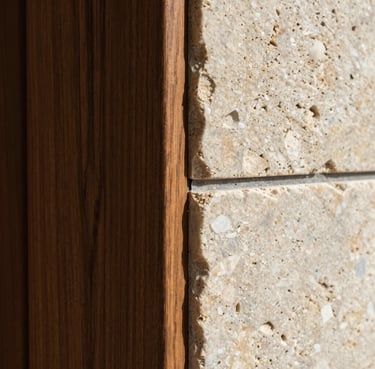 Extreme close-up of a perfectly executed architectural joint, dark oak wood panel meeting raw travertine stone under crisp natural light