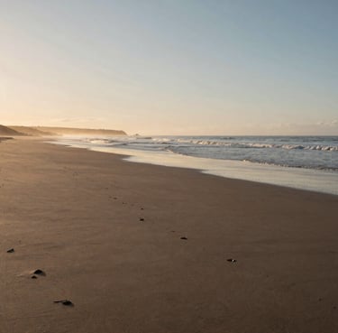 Wide shot of a peaceful Portuguese coastline at sunrise, soft sand beach, cinematic lighting, calm and authentic atmosphere.