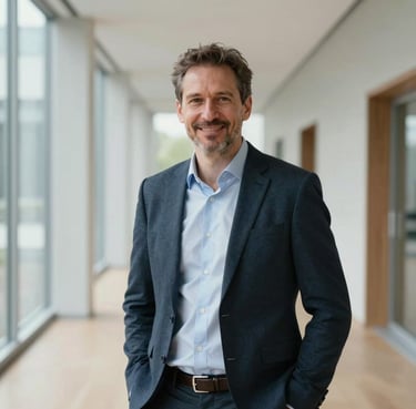 A portrait of a professional man in his 40s wearing business casual attire, standing in a bright Zentraleuropäisch / Deutsch modern building corridor, smiling confidently.