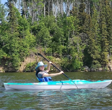 a woman in a blue shirt is kayaking on a lake