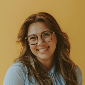 a white woman smiling in front of yellow background