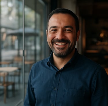 A professional Anatolian / Turkish male client smiling in front of a newly installed guillotine glass system in a modern cafe, soft morning light, professional photography.