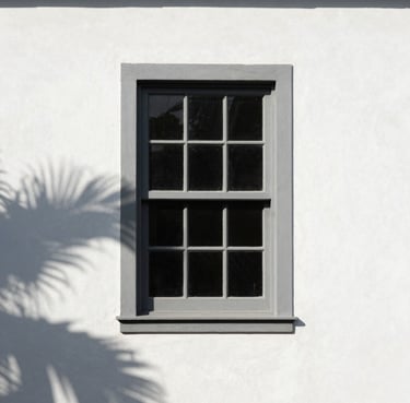 Minimalist facade detail, white plastered wall, storm gray window frame, tropical leaf shadow, bright Brazilian sun.