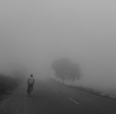 A misty day and a road with a single cycle-rider.