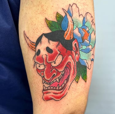 a tattoo of a demon mask on a man's arm made at Inari Tattoo