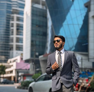 Professional businessman in a grey suit and sunglasses posing in a modern city business district.