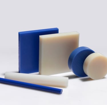 Assorted blue and white industrial plastic sheets, rods, and discs for engineering fabrication.