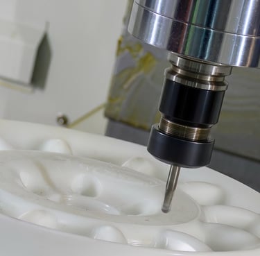 Automated CNC milling machine precision cutting a white plastic industrial component.