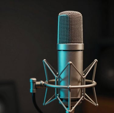 A close-up shot of a high-end vintage condenser microphone in a dimly lit studio, with soft neon cyan light reflecting off its metallic surface. Dark charcoal background, cinematic atmosphere in a South American / Colombian recording studio.