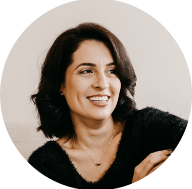 A smiling professional woman with short dark hair wearing a black fuzzy sweater in a profile headshot.