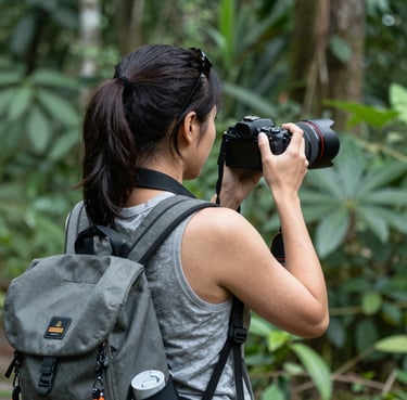 A candid portrait of a smiling traveler holding a camera against a sunset backdrop.