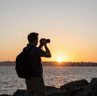 A candid portrait of a smiling traveler holding a camera against a sunset backdrop.