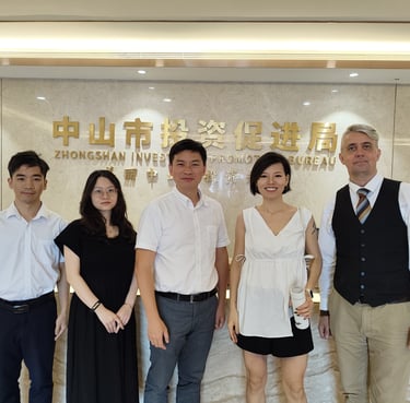 A group of professionals standing in front of the Zhongshan Investment Promotion Bureau sign.