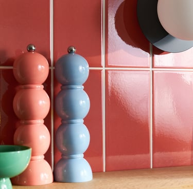 Glossy coral wall tiles with white grout in a modern kitchen splashback, featuring pastel pink 