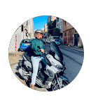 رجل يرتدي قميصًا أخضر وبنطالًا أبيض يجلس على دراجة نارية