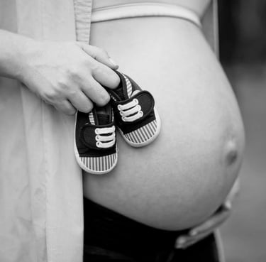 pregnant-woman-holding-baby-shoes