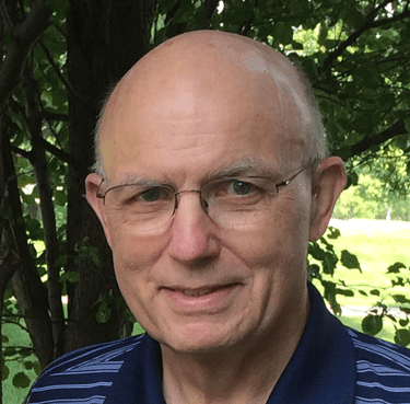 jim-bowman-informal-outdoor-headshot- wearing-blue-polo-shirt beneath-a-shady-tree