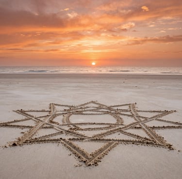 Cinematic wide shot of a tranquil beach at sunset, warm terracotta orange hues in the sky, a large intricate geometric sand drawing in the foreground on soft sand off-white.