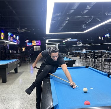 man sitting on pool table playing a shot