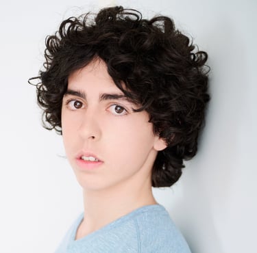 a young man with a curly haircut and a blue shirt headshot