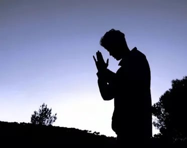 a silhouette of a man praying in the evening for bible answers