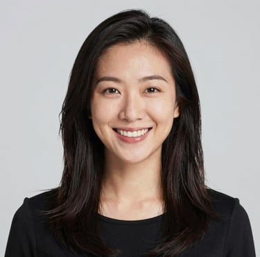 A smiling woman with curly hair enjoying a sunny outdoor cafe.