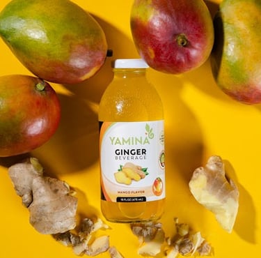 a bottle of ginger infused drink surrounded by mangos and ginger