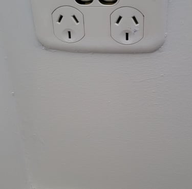 Broken white double power point electrical outlet on a wall