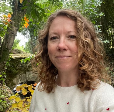 Headshot of Iona Reading standing in front of trees and a bridge