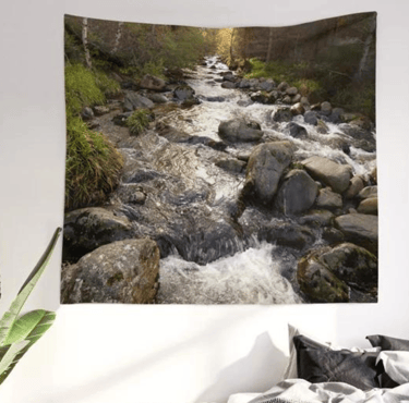 Wall tapestry on wall with autumnal river printed on it, bed in situ underneath.