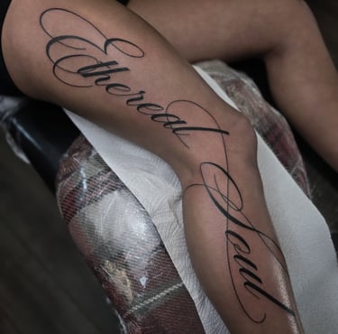 Cursive script tattoo on a leg featuring the words Ethereal Soul in elegant black ink.