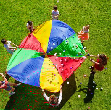 a group of people playing with a giant colorful umbrella